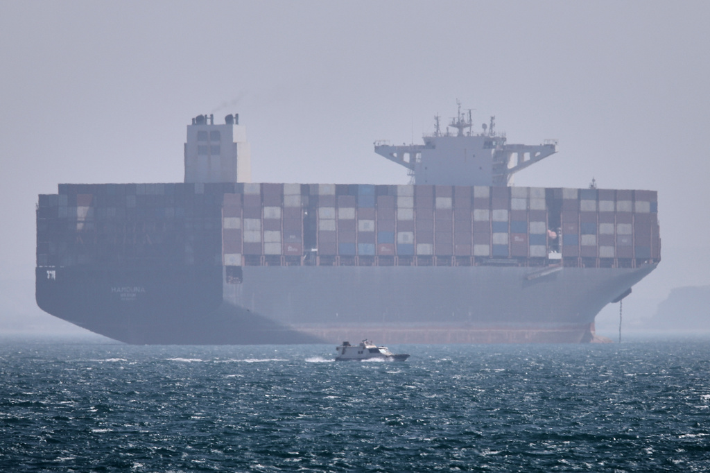 A container ship sits at anchor as a small motorboat passes in the foreground in the Strait of Hormuz off Bandar Abbas, Iran, Saturday, May 2, 2026. (Amirhosein Khorgooi/ISNA via AP)