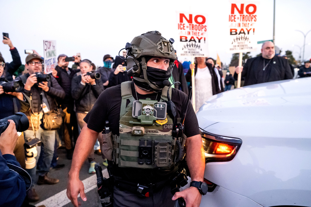 A U.S. Border Patrol officer tries to clear protesters while entering Coast Guard Base Alameda on Thursday, Oct. 23, 2025, in Oakland, Calif. (AP Photo/Noah Berger)