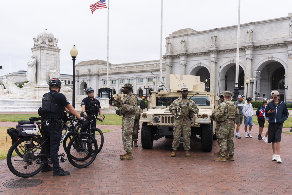 U.S. Capitol Police officers on bike patrol talk to District of Columbia Army National Guardsmen standing next to their Humvee military utility vehicle, outside Union Station near the U.S. Capitol in Washington, Tuesday, Aug. 19, 2025. (AP Photo/Manuel Balce Ceneta)