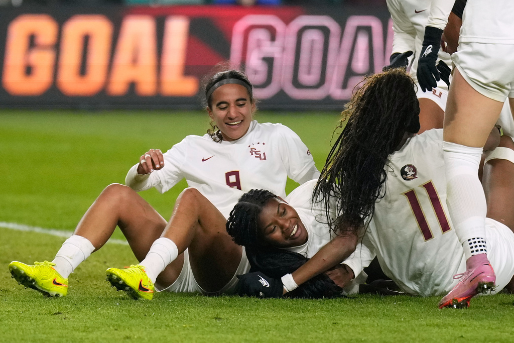 Florida State's Wrianna Hudson, center, is congratulated by teammates Taylor Suarez (9) and Jordynn Dudley (11) after scoring during the second half of the NCAA college soccer tournament final against Stanford Monday, Dec. 8, 2025, in Kansas City, Mo. (AP Photo/Charlie Riedel)
