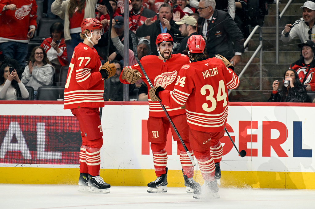 Detroit Red Wings left wing David Perron, middle, is congratulated by defenseman Simon Edvinsson, left, and left wing Carter Mazur during the second period of an NHL hockey game, Saturday, April 11, 2026, in Detroit. (AP Photo/Jose Juarez)