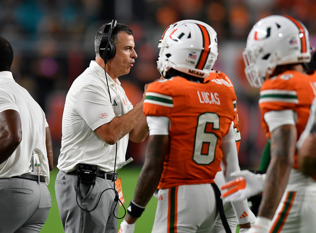 Miami head coach Mario Cristobal talks to his team during the first half of an NCAA college football game against Louisville, Friday, Oct. 17, 2025, in Miami Gardens, Fla. (AP Photo/Michael Laughlin)