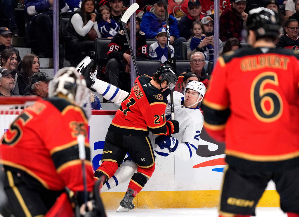 Toronto Maple Leafs' Brandon Carlo (25) is knocked off his skates along the boards by Ottawa Senators' Nick Cousins (21) during first-period NHL hockey game action in Ottawa, Ontario, Saturday, March 21, 2026. (Justin Tang/The Canadian Press via AP)