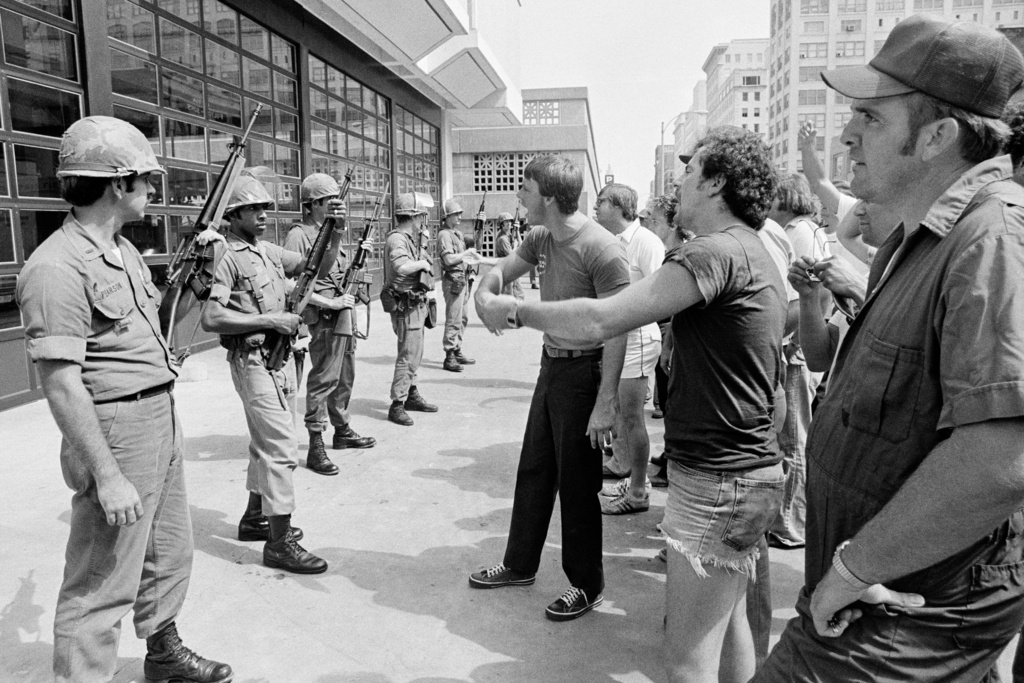 FILE - Striking firefighters yell at working firefighters inside the fire station, as Tennessee National Guard troops guard the front entrance, on Aug. 15, 1978, in downtown Memphis. (AP Photo/Chuck Robinson, File)
