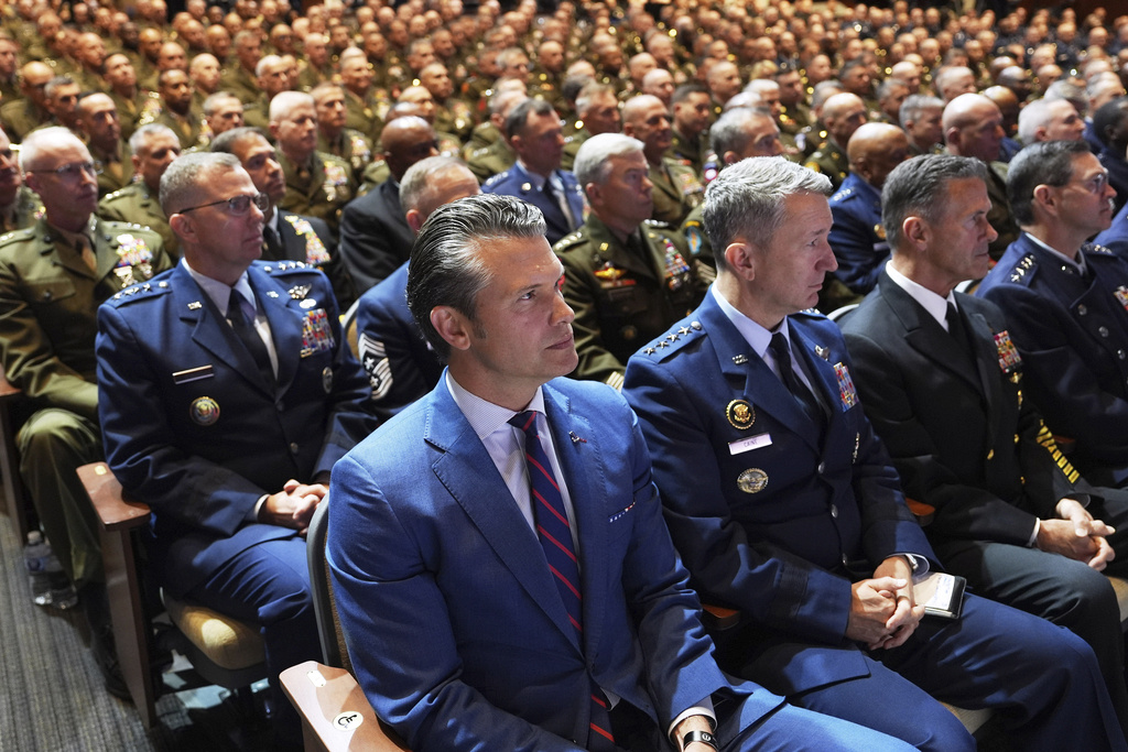 Defense Secretary Pete Hegseth, center, sitting with Chairman of the Joint Chiefs of Staff Air Force Gen. Dan Caine, third from right, and U.S. military senior leadership as they listen to President Donald Trump speaks at Marine Corps Base Quantico, Tuesday, Sept. 30, 2025 in Quantico, Va. (AP Photo/Evan Vucci)