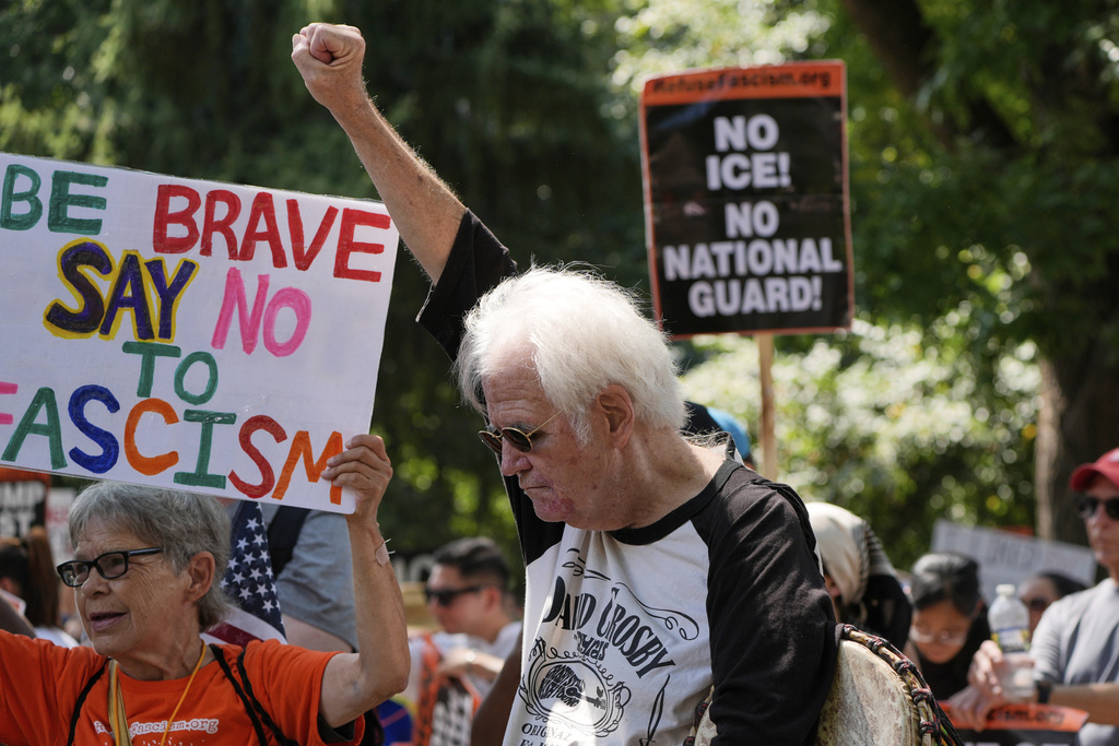 Activists carry signs during a protest against President Donald Trump's federal takeover of policing of the District of Columbia, Saturday, Aug. 16, 2025, in Washington. (AP Photo/Alex Brandon)