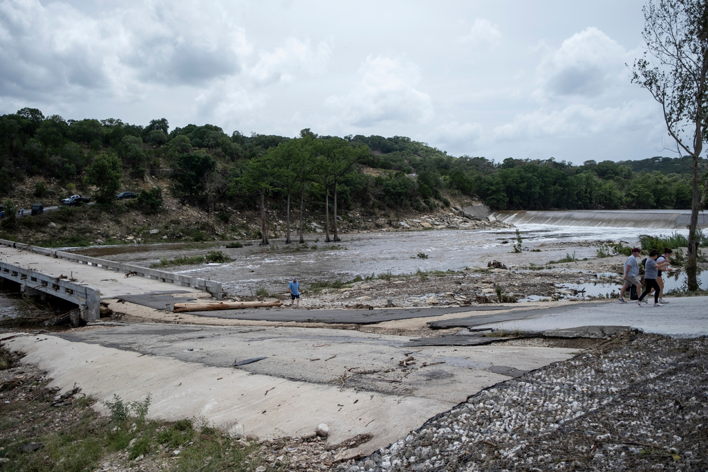 People walk along the Guadalupe River after heavy floods on Friday, July 17, 2026, in Ingram, Texas. (AP Photo/Joel Angel Juarez)
