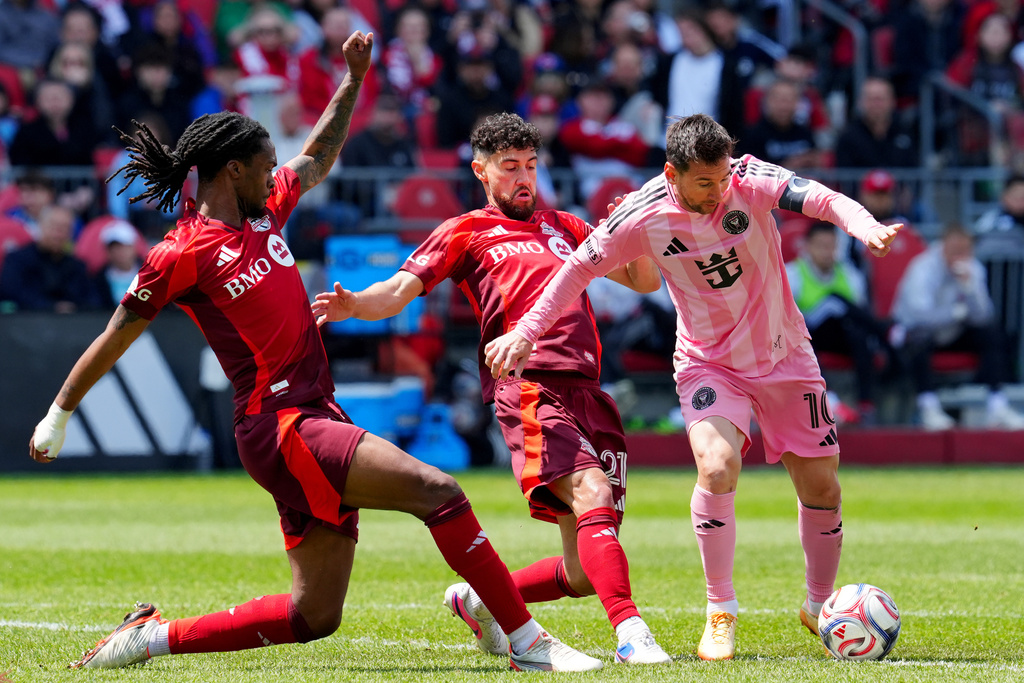 Inter Miami CF midfielder Lionel Messi (10) moves the ball around Toronto FC defender Zane Monlouis (12) and teammate Jonathan Osorio (21) during first half MLS soccer in Toronto on Saturday, May 9, 2026. (Frank Gunn /The Canadian Press via AP)