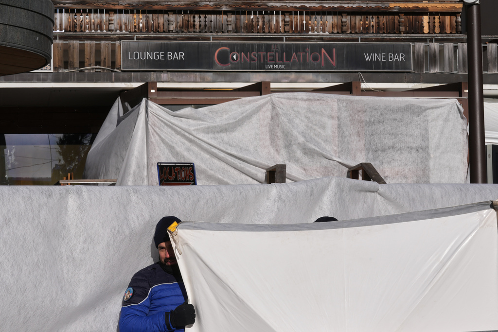Security stands in front of the sealed off Le Constellation bar, where a devastating fire left dead and injured during the New Year's celebrations in Crans-Montana, Swiss Alps, Switzerland, Friday morning, Jan. 2, 2026. (AP Photo/ Antonio Calanni)