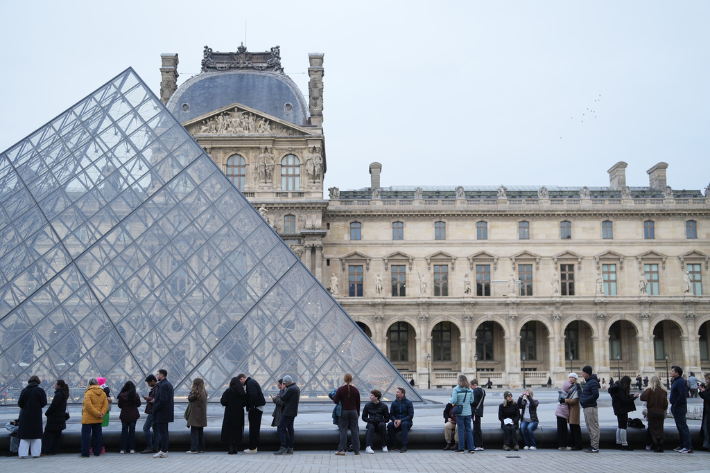 FILE - People wait for the Louvre museum to open as employees at the Louvre Museum vote to extend a strike that has disrupted operations at the world's most visited museum, Dec. 18, 2025 in Paris. (AP Photo/Thibault Camus, File)