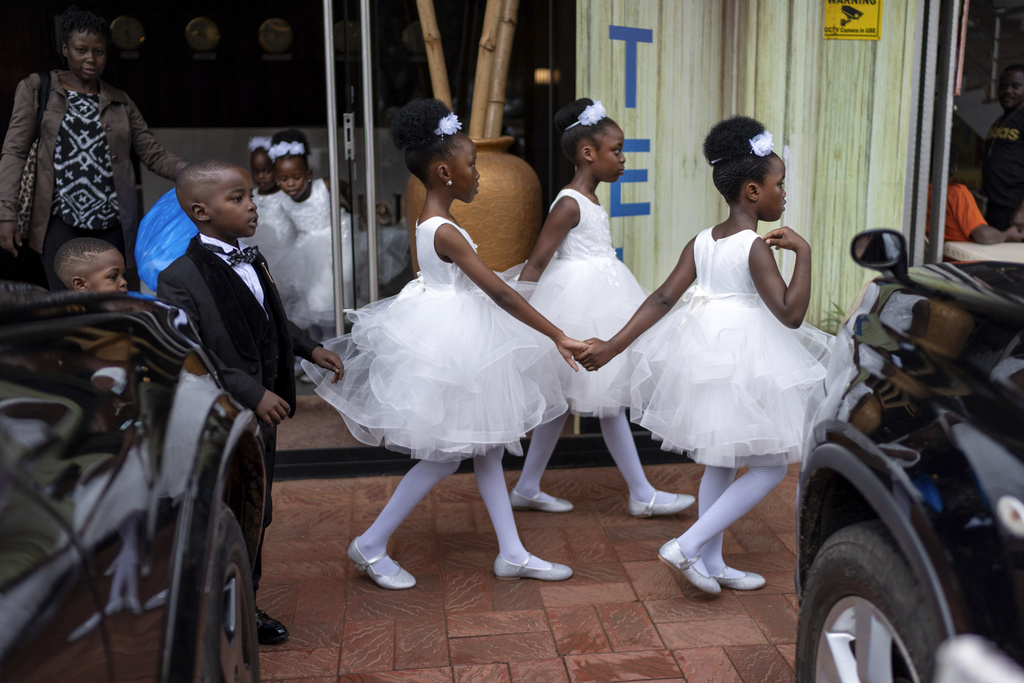 Young girls, part of a wedding party, hold hands as they leave a hotel to attend the ceremony, Saturday, Nov. 23, 2024, in Kampala, Uganda, home to some 25 million children, about half of the country's population. (AP Photo/David Goldman)