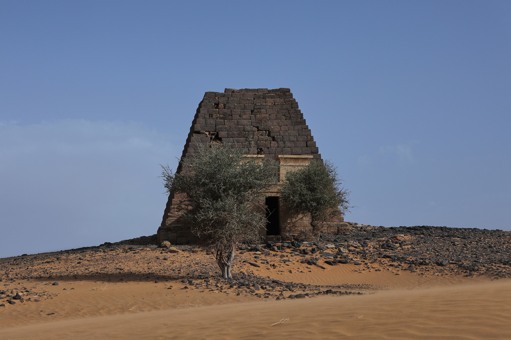 A tree stands in front of a pyramid at the Meroe archaeological site in Bejrawiya, Sudan, Saturday, Aug. 1, 2026. (AP Photo/Mohnd Blal)