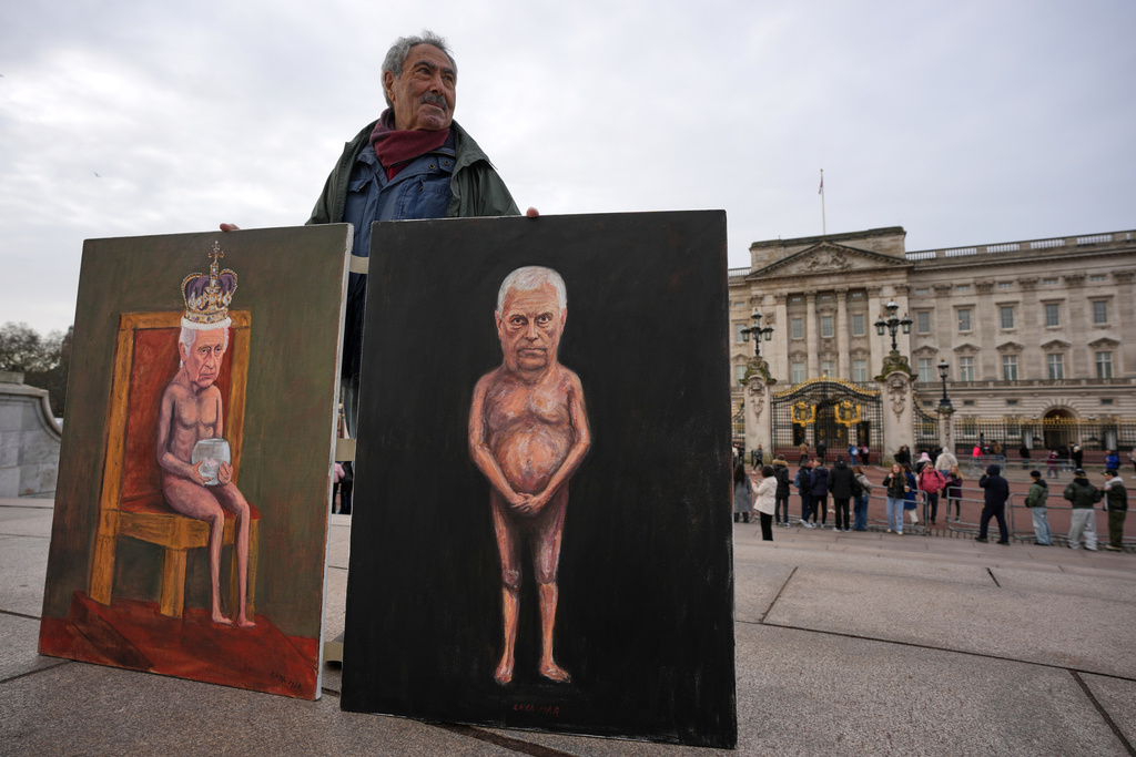 Artist Kaya Mar sposes with the newest edition of his paintings for the media in front of Buckingham Palace, London, Friday, Feb. 20, 2026 after Andrew Mountbatten-Windsor was arrested and held for hours by British police on suspicion of misconduct in public office related to his links to Jeffrey Epstein.(AP Photo/Kin Cheung)