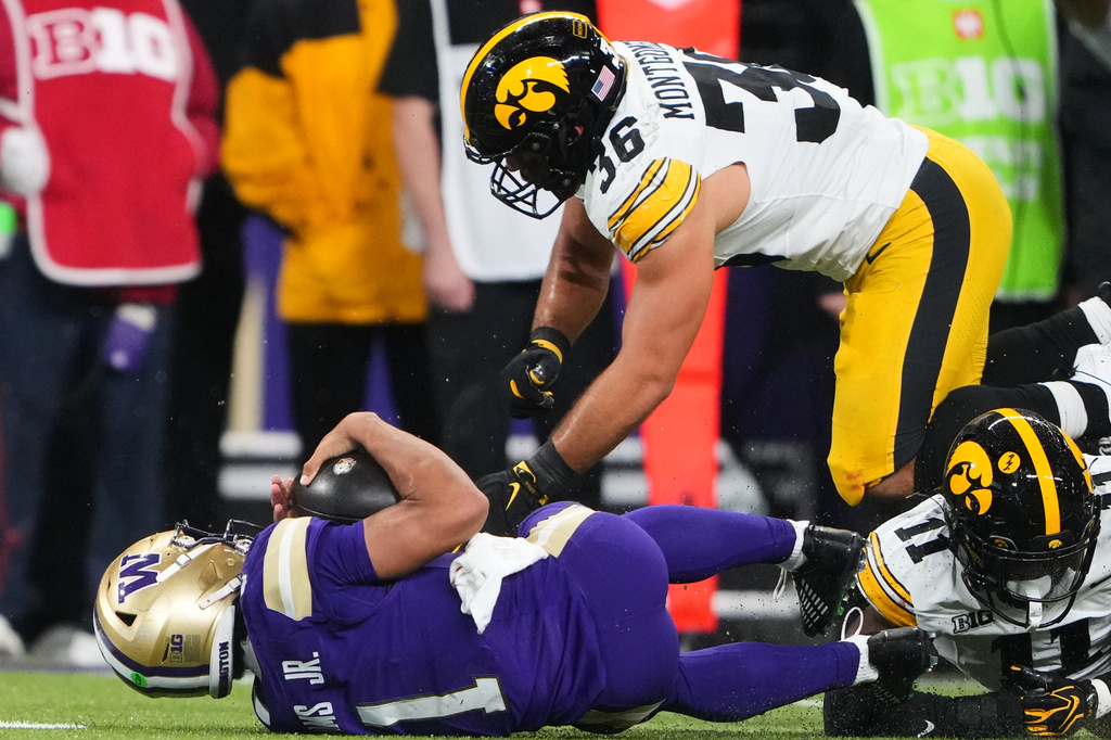 Washington quarterback Demond Williams Jr. is tackled by Iowa linebacker Jayden Montgomery (36) and defensive back Jacob Wallace (11) during the first half of an NCAA college football game, Friday, Oct. 9, 2026, in Seattle. (AP Photo/Lindsey Wasson)