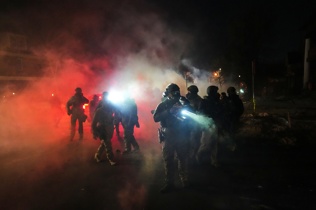 FILE - Law enforcement officers stand amid tear gas at the scene of a reported shooting, Jan. 14, 2026, in Minneapolis. (AP Photo/Adam Gray, File)