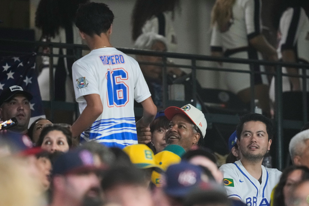 Former professional baseball player Manny Ramirez, second from right, greets a fan during the fifth inning of a World Baseball Classic game between the United States and Brazil, Friday, March 6, 2026, in Houston. (AP Photo/Ashley Landis)