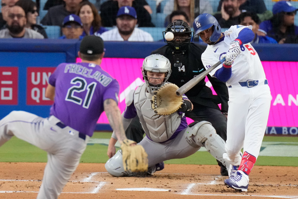 Los Angeles Dodgers' Mookie Betts, right, hits a two-run home run as Colorado Rockies pitcher Kyle Freeland, left, and catcher Hunter Goodman watch during the first inning of a baseball game Tuesday, May 26, 2026, in Los Angeles. (AP Photo/Mark J. Terrill)