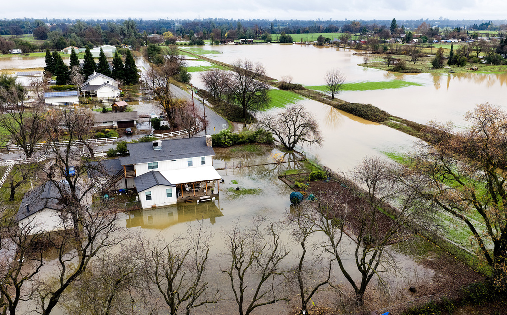 Floodwaters cover a yard and fields following heavy rains, on Monday, Dec. 22, 2025, in Redding, Calif. (AP Photo/Noah Berger)