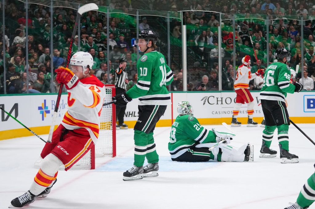 Dallas Stars goaltender Jake Oettinger, center, reacts after giving up a goal to Calgary Flames center Martin Pospisil, second from right, during the second period of an NHL hockey game Tuesday, April 7, 2026, in Dallas. (AP Photo/Julio Cortez)