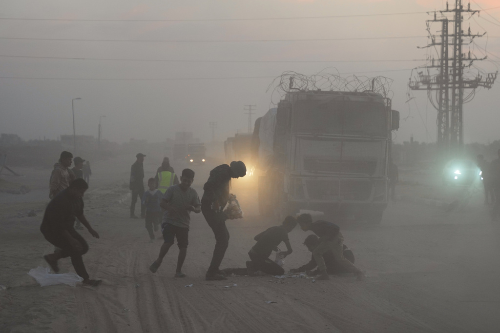 Palestinians rush toward trucks carrying aid from the World Food Programme (WFP) as they drive through Deir al-Balah in central Gaza, Saturday, Nov. 8, 2025. (AP Photo/Abdel Kareem Hana)