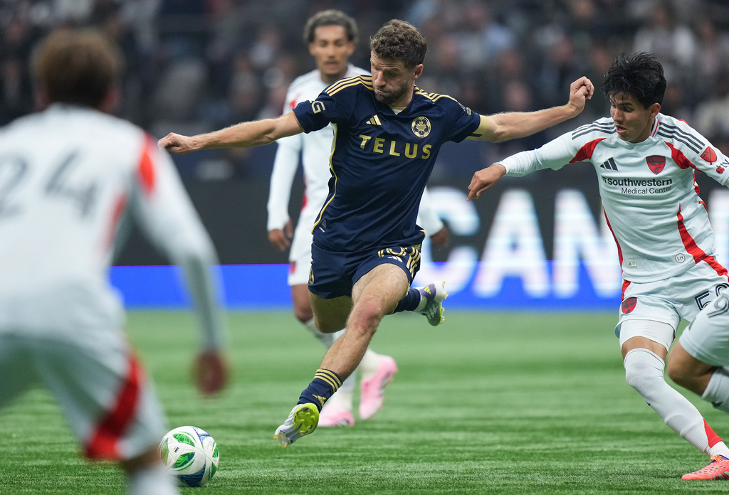 Vancouver Whitecaps' Thomas Muller, center, shoots on goal as FC Dallas' Diego Garcia, right, defends during the second half of an MLS soccer match in Vancouver, British Columbia, Saturday, Oct. 18, 2025. (Darryl Dyck/The Canadian Press via AP)