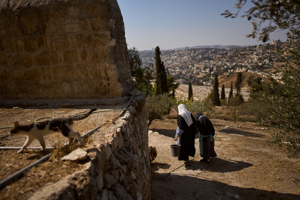Sister Marie Benedicte, left, and Sister Colomba, two Catholic nuns, walk in their monastery's garden to harvest olives on the Mount of Olives, in Jerusalem, Friday, Oct. 17, 2025. (AP Photo/Oded Balilty)