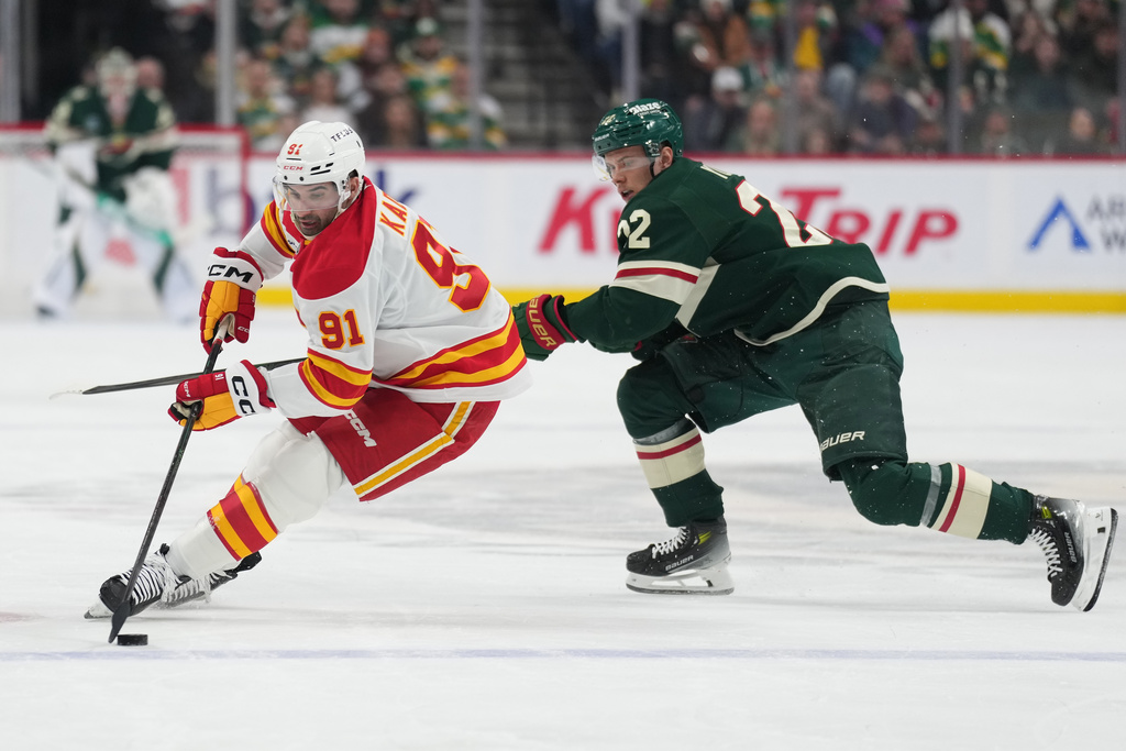 Calgary Flames center Nazem Kadri (91) skates with the puck as Minnesota Wild right wing Danila Yurov follows during the first period of an NHL hockey game, Thursday, Jan. 29, 2026, in St. Paul, Minn. (AP Photo/Abbie Parr)