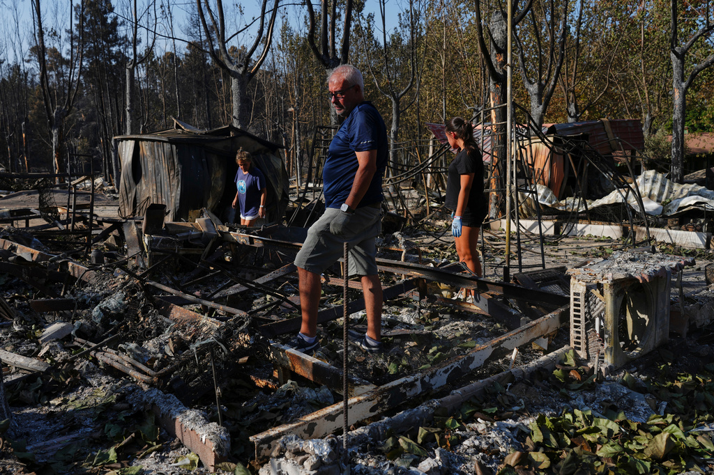 FILE - Maria del Carmen, left, her daughter Maria del Carmen Lopez, right, and her partner Mario Gonzalez, center, collect their belongings after their bungalows were ravaged by a wildfire at a campsite in Valle de Iruelas, Spain, July 30, 2026. (AP Photo/Manu Fernandez, File)
