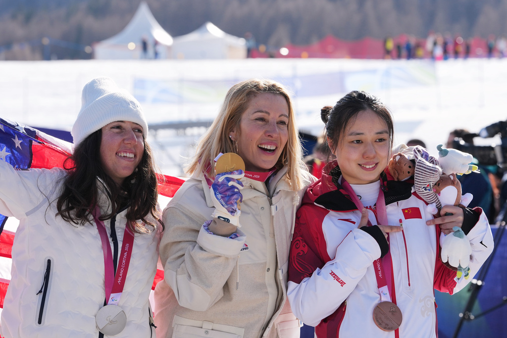 Silver medalist Kate Delson, of the United States, from left, gold medalist Cecile Hernandez, of France, and bronze medalist Wang Xinyu, of China, pose after the women's snowboard cross SB-LL2 final at the 2026 Winter Paralympics, in Cortina d'Ampezzo, Italy, Sunday, March 8, 2026. (AP Photo/Evgeniy Maloletka