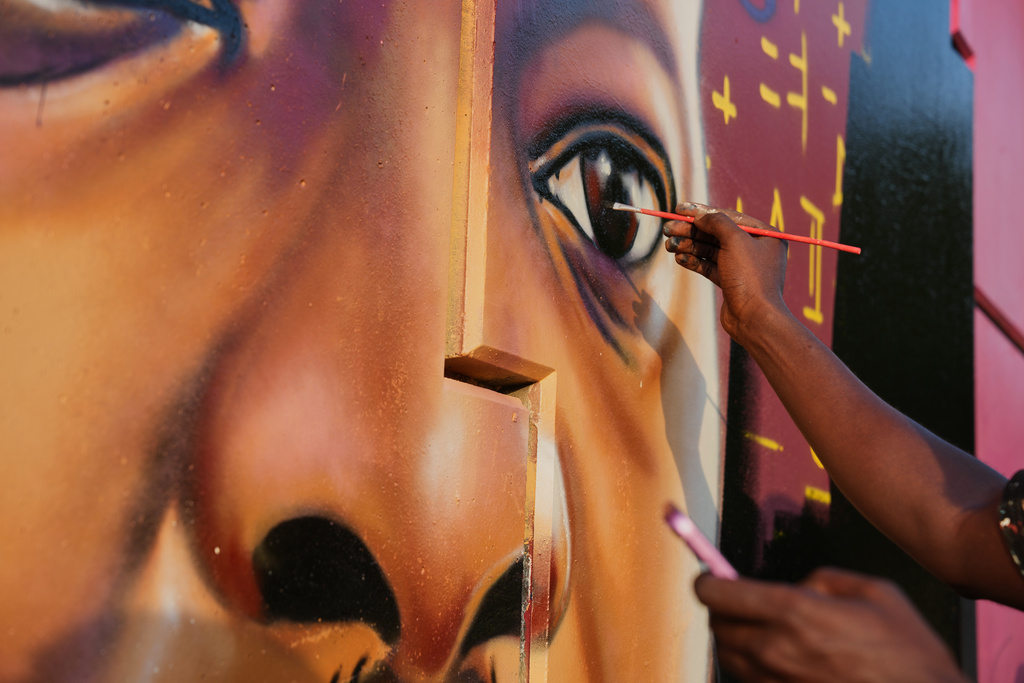Graffiti artist Omar Diaw paints details on a mural depicting Guinea's President Mamadi Doumbouya in Conakry, Guinea, Saturday, Sep. 20, 2025. (AP Photo/Misper Apawu)