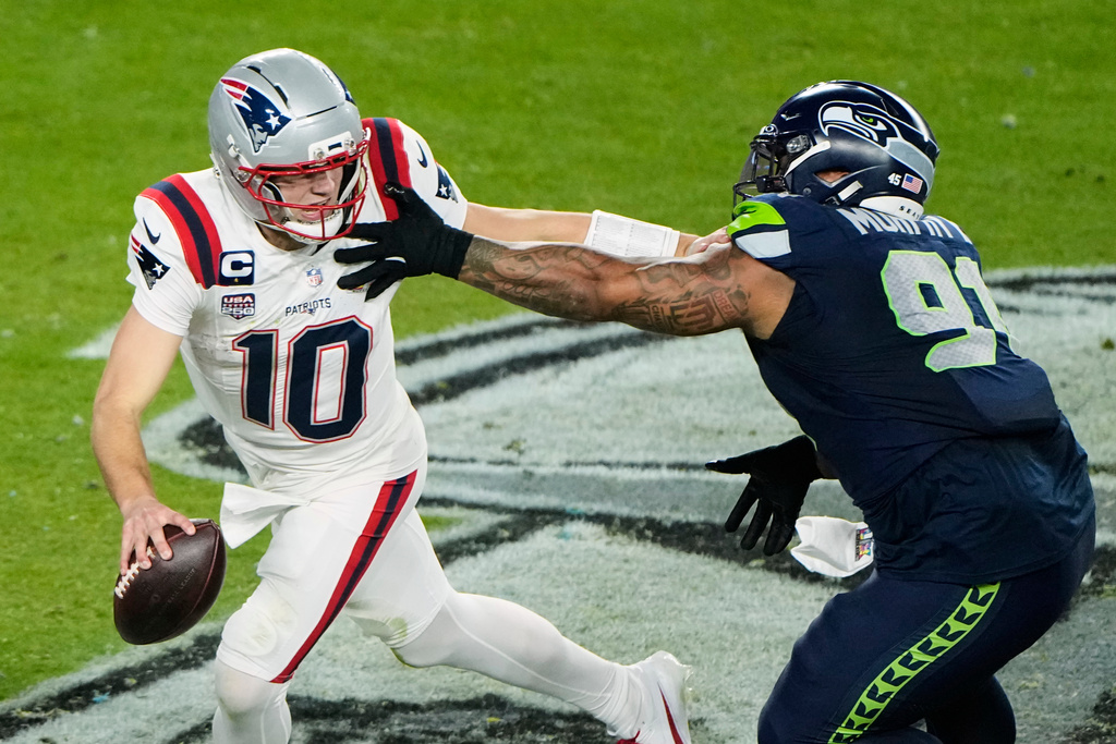 New England Patriots quarterback Drake Maye (10) escapes pressure from Seattle Seahawks defensive tackle Byron Murphy II (91) during the second half of the NFL Super Bowl 60 football game, Sunday, Feb. 8, 2026, in Santa Clara, Calif. (AP Photo/Charlie Riedel)
