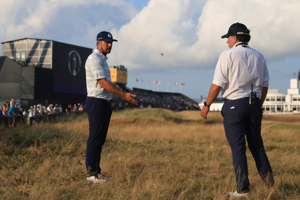 Bryson DeChambeau of the United States, left speaks to a rules office before playing his shot on the 18th hole during the third day of the British Open Golf championships at Royal Birkdale golf club, in Southport, England, Saturday, July 18, 2026. (AP Photo/Peter Morrison)