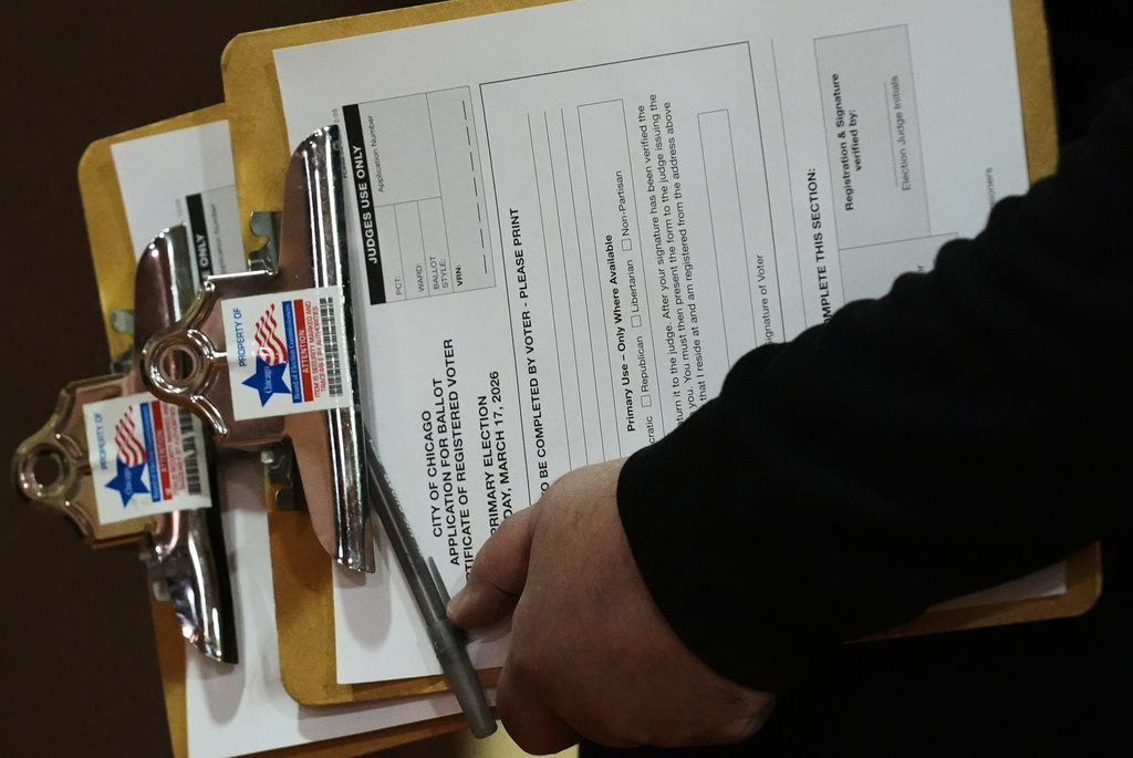 A voting official holds registration forms to vote on Election Day at Chicago Park District Loyola field house in Chicago, Tuesday, March 17, 2026. (AP Photo/Nam Y. Huh)