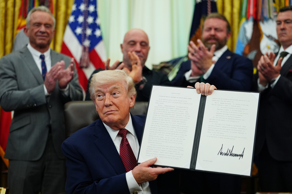 President Donald Trump holds up a signed executive order in the Oval Office of the White House, Saturday, April 18, 2026, in Washington. (AP Photo/Julia Demaree Nikhinson)