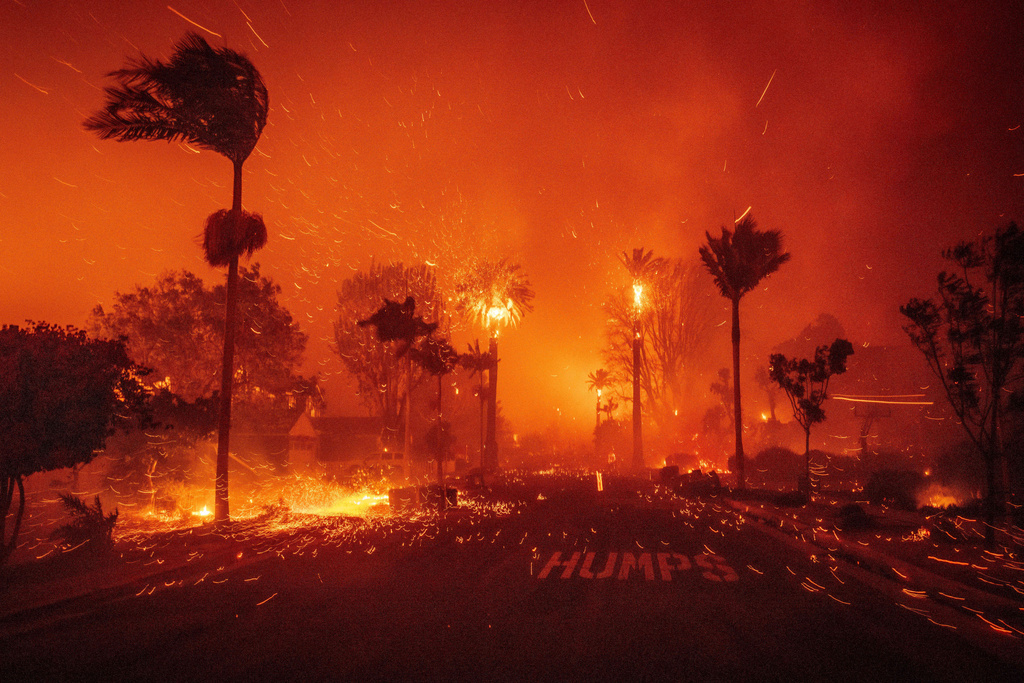FILE - Embers blow down a street as the Palisades Fire ravages a neighborhood amid high winds in the Pacific Palisades neighborhood of Los Angeles, Jan. 7, 2025. (AP Photo/Ethan Swope, File)