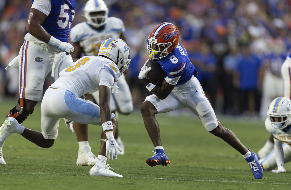 Florida wide receiver Vernell Brown III (8) makes yards under pressure from LIU Brooklyn defensive back Marshall Washington Jr. (8) during the first half of an NCAA college football game Saturday, Aug. 30, 2025, in Gainesville, Fla. (AP Photo/Alan Youngblood)