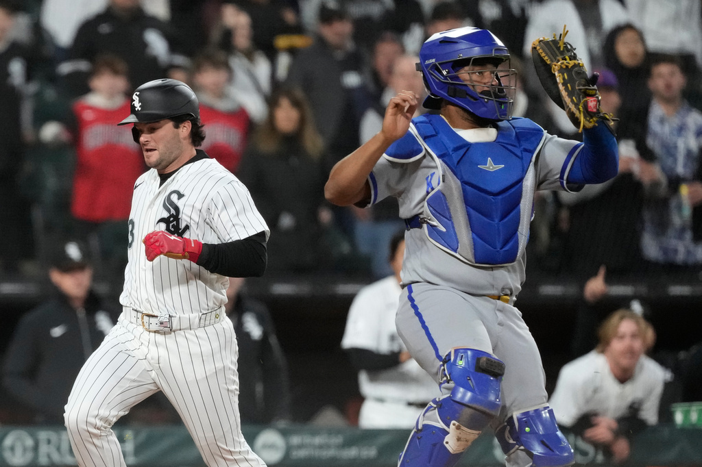 Chicago White Sox's Andrew Benintendi, left, scores on a two-run double by Jarred Kelenic as Kansas City Royals catcher Elias Díaz waits for the ball during the fifth inning of a baseball game in Chicago, Wednesday, May 13, 2026. (AP Photo/Nam Y. Huh)