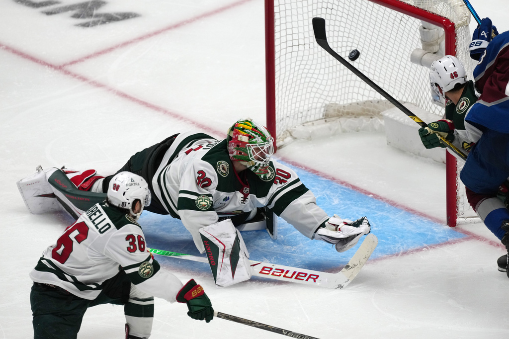 Minnesota Wild goaltender Jesper Wallstedt, center, misses a goal shot by Colorado Avalanche defenseman Brett Kulak as Minnesota right wing Mats Zuccarello, left, and defenseman Jared Spurgeon cover in overtime of Game 5 of an NHL Stanley Cup hockey second-round playoff series Wednesday, May 13, 2026, in Denver. (AP Photo/David Zalubowski)