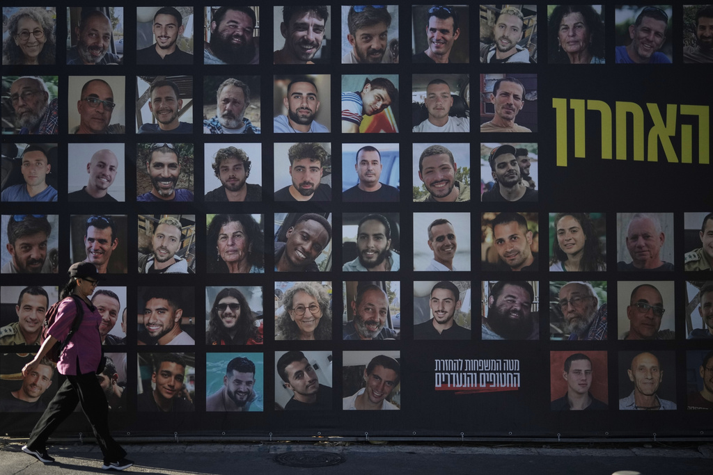 A woman walks past a banner with photographs of hostages who were kidnapped and held by Hamas in the Gaza Strip, in Jerusalem, Tuesday, Oct. 7, 2025, on the second anniversary of Hamas' cross-border attack on Israel on Oct. 7, 2023, which sparked the ongoing war in Gaza. (AP Photo/Leo Correa)