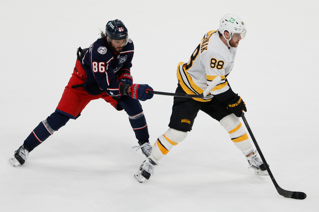 Boston Bruins' David Pastrnak, right, carries the puck into the offfensive zone as Columbus Blue Jackets' Kirill Marchenko defends during the overtime period of an NHL hockey game, Sunday, March 29, 2026, in Columbus, Ohio. (AP Photo/Jay LaPrete)