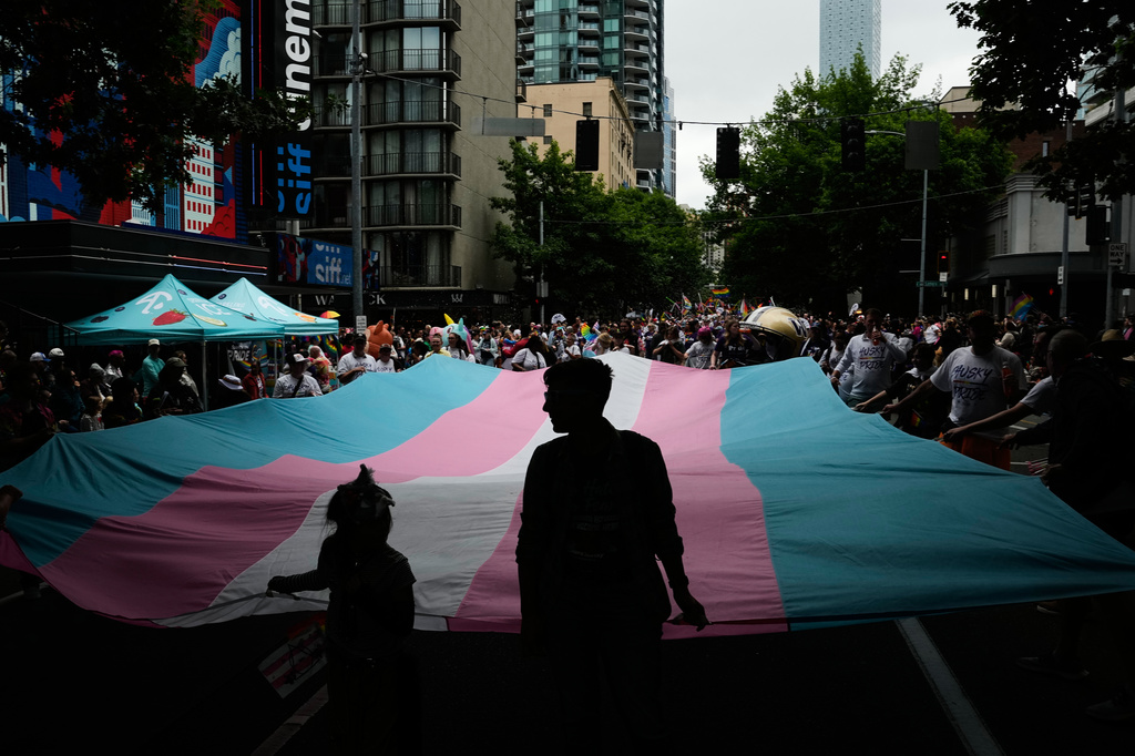 People help carry a transgender pride flag while marching with the University of Washington during the Seattle Pride Parade, Sunday, June 28, 2026, in Seattle. (AP Photo/Lindsey Wasson)