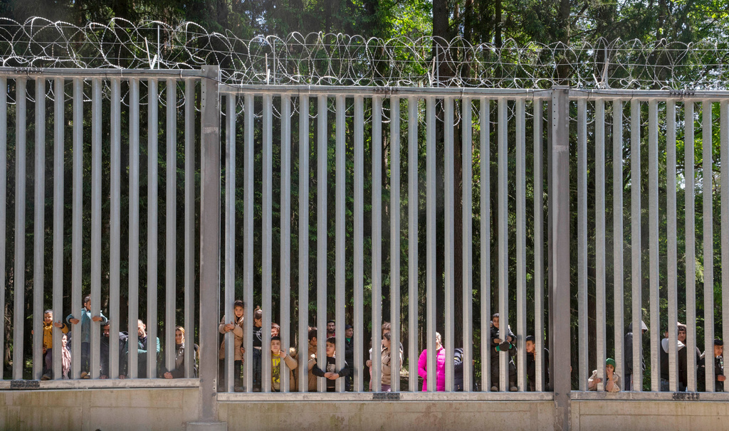 FILE - Members of a group of some 30 migrants seeking asylum look through the railings of a wall that Poland has built on its border with Belarus to stop massive migrant pressure in Bialowieza, Poland, on May 28, 2023. (AP Photo/Agnieszka Sadowska, File)