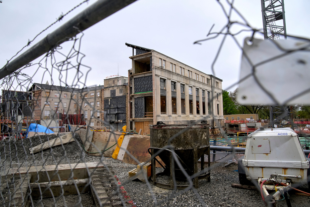 FILE - A building in the Federal Reserve complex, which is under construction, is seen through a hole in construction fencing, April 7, 2025, in Washington. (AP Photo/Jacquelyn Martin, File)