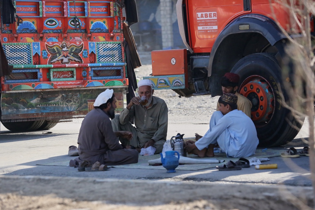 Drivers sit beside their trucks as cargo vehicles bound for Pakistan remain stranded on the Afghan side of the Torkham border crossing, which stayed closed after clashes, in Nangarhar province, Afghanistan, Tuesday, Oct. 14, 2025. (AP Photo/Wahidullah Kakar)