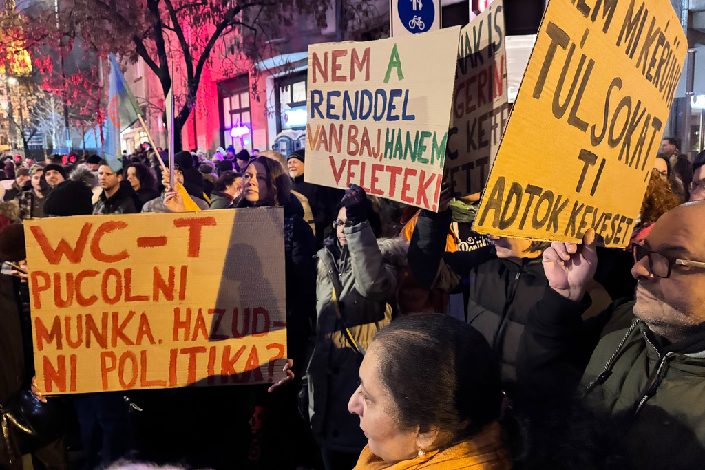 Demonstrators hold signs, one reading, at left, reading "Cleaning toilets is work but lying is politics?" at a protest against a Hungarian government minister called over comments he made about the Roma minority, in Budapest, Hungary, Saturday, Jan. 31, 2026. (AP Photo/Bela Szandelszky)