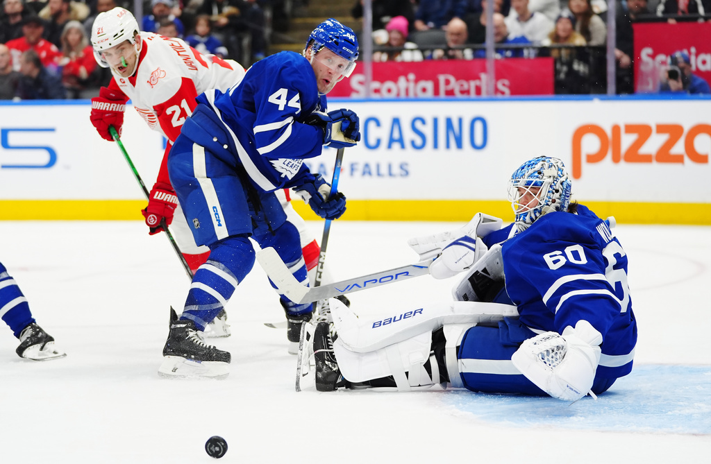 Toronto Maple Leafs goaltender Joseph Woll (60) makes a save as Morgan Rielly (44) battles with Detroit Red Wings' James van Riemsdyk (21) during the third period of an NHL hockey game in Toronto, Wednesday, Jan. 21, 2026. (Frank Gunn/The Canadian Press via AP)