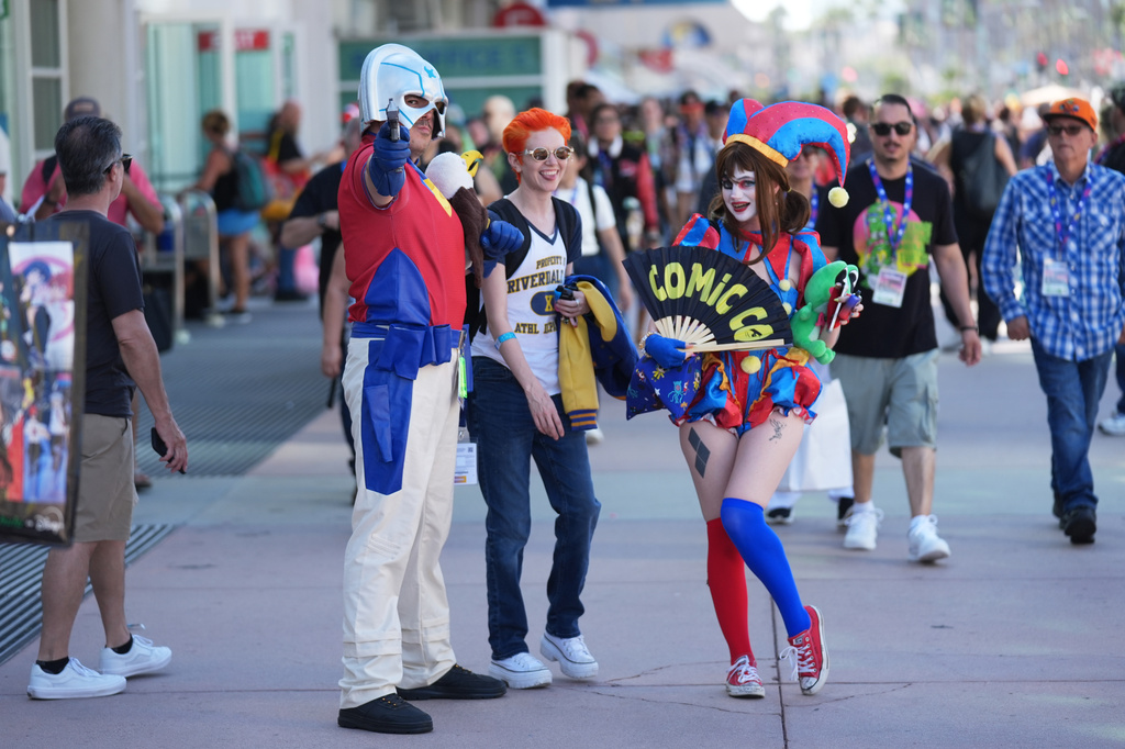 Dorian Reyes Black of Los Angeles, dressed as Peacemaker, from left, Connor Bright of Los Angeles, dressed as Archie from "Riverdale" and Emily Rose of Los Angeles, dressed as Pomni from "The Amazing Digital Circus" attend Comic-Con International on Thursday, July 23, 2026, in San Diego. (AP Photo/Chris Pizzello)