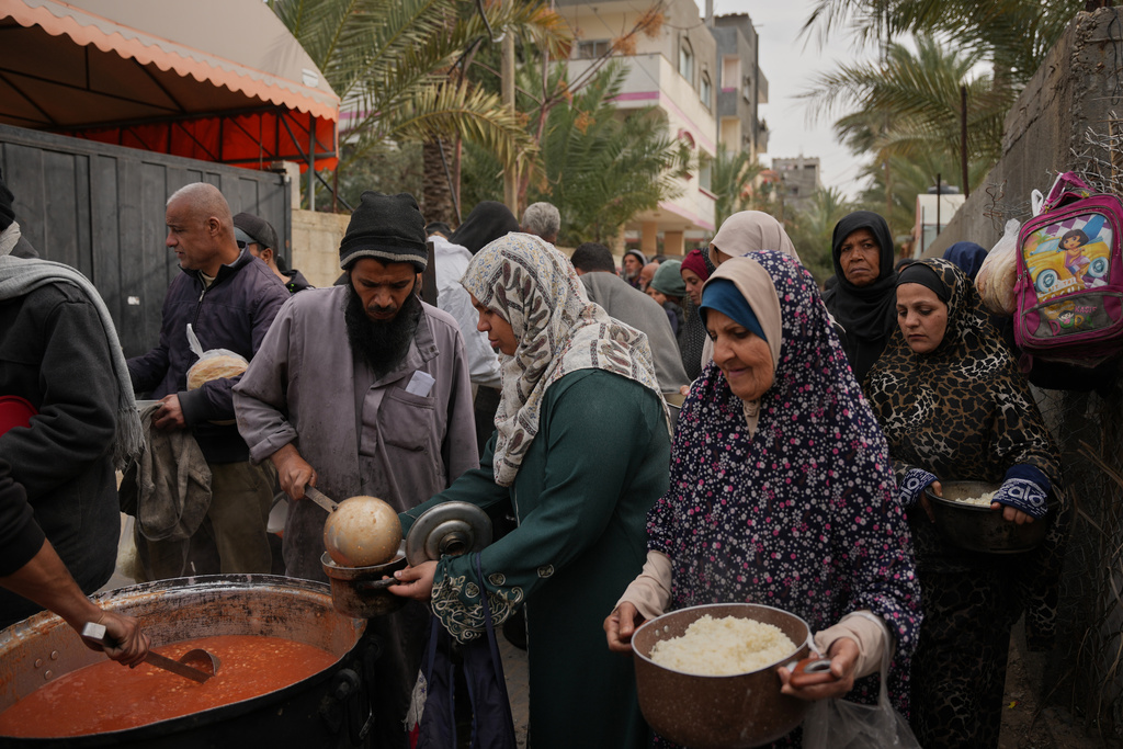 Palestinian women receive donated food at a community kitchen in Deir al-Balah, central Gaza Strip, Wednesday, Jan. 21, 2026. (AP Photo/Abdel Kareem Hana)