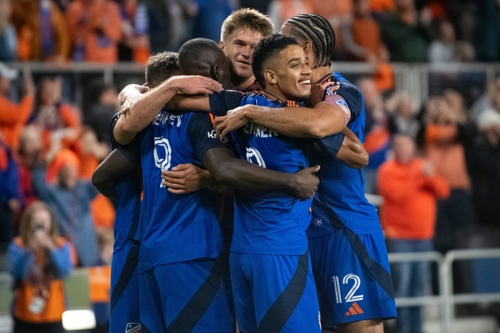 FC Cincinnati forward Brenner, center, looks toward the field while embracing his teammates after forward Kévin Denkey (9) scored during the second half of Game 1 in the first round of MLS soccer's Eastern Conference playoffs against the Columbus Crew, Monday, Oct. 27, 2025, in Cincinnati. (AP Photo/Tanner Pearson)