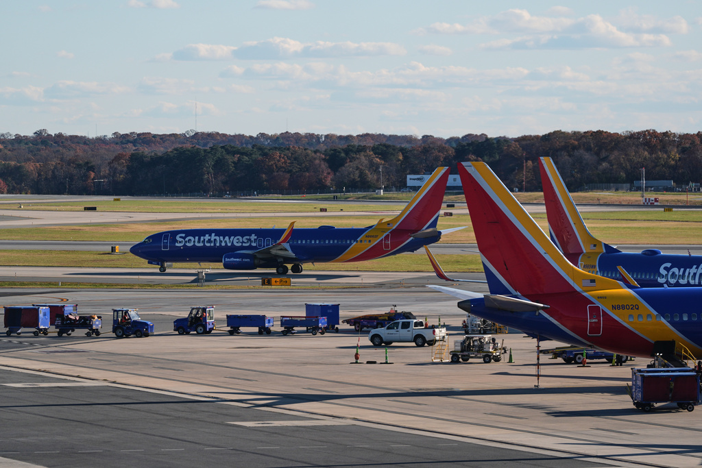 A Southwest Airlines plane taxis down the runway as others sit at gates at Baltimore/Washington International Thurgood Marshall Airport in Baltimore, Monday, Nov. 10, 2025. (AP Photo/Stephanie Scarbrough)